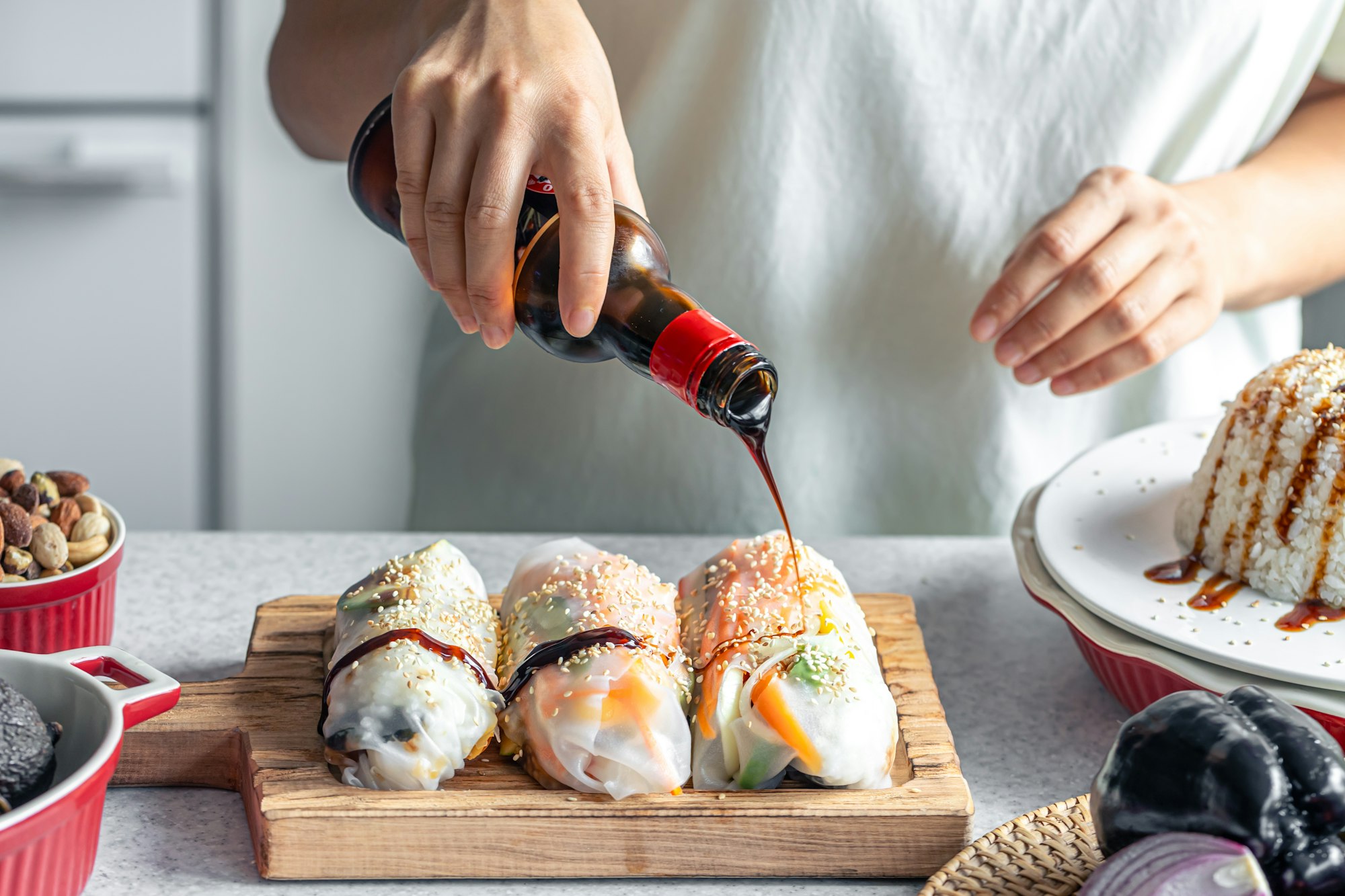 A woman pours sauce over homemade spring rolls.