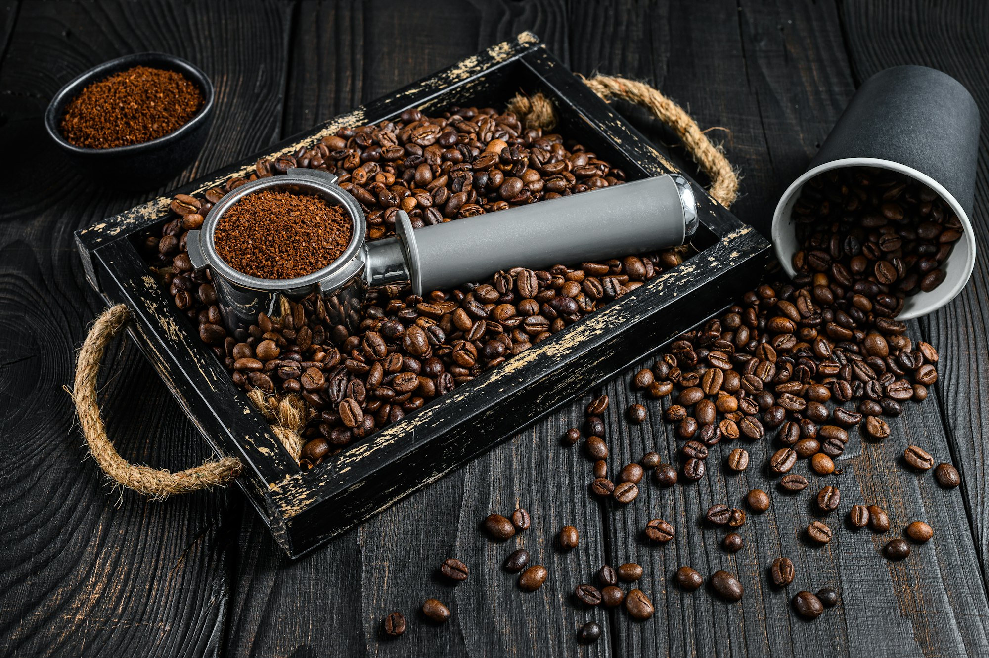 Ground Coffee in Portafilter for Espresso in a wooden tray with coffee beans.